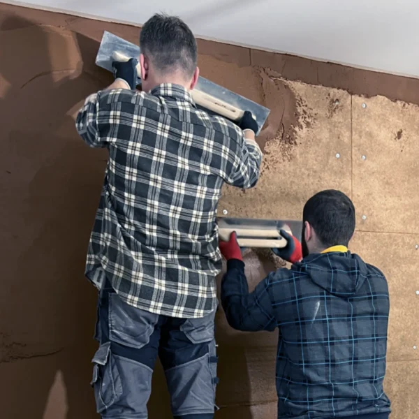 Application of clay plaster on a compressed clay board using a trowel.​